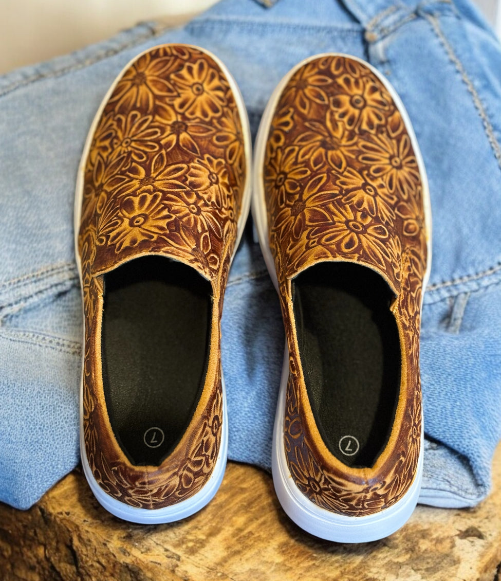 Brown sneakers on a wooden table with jeans.