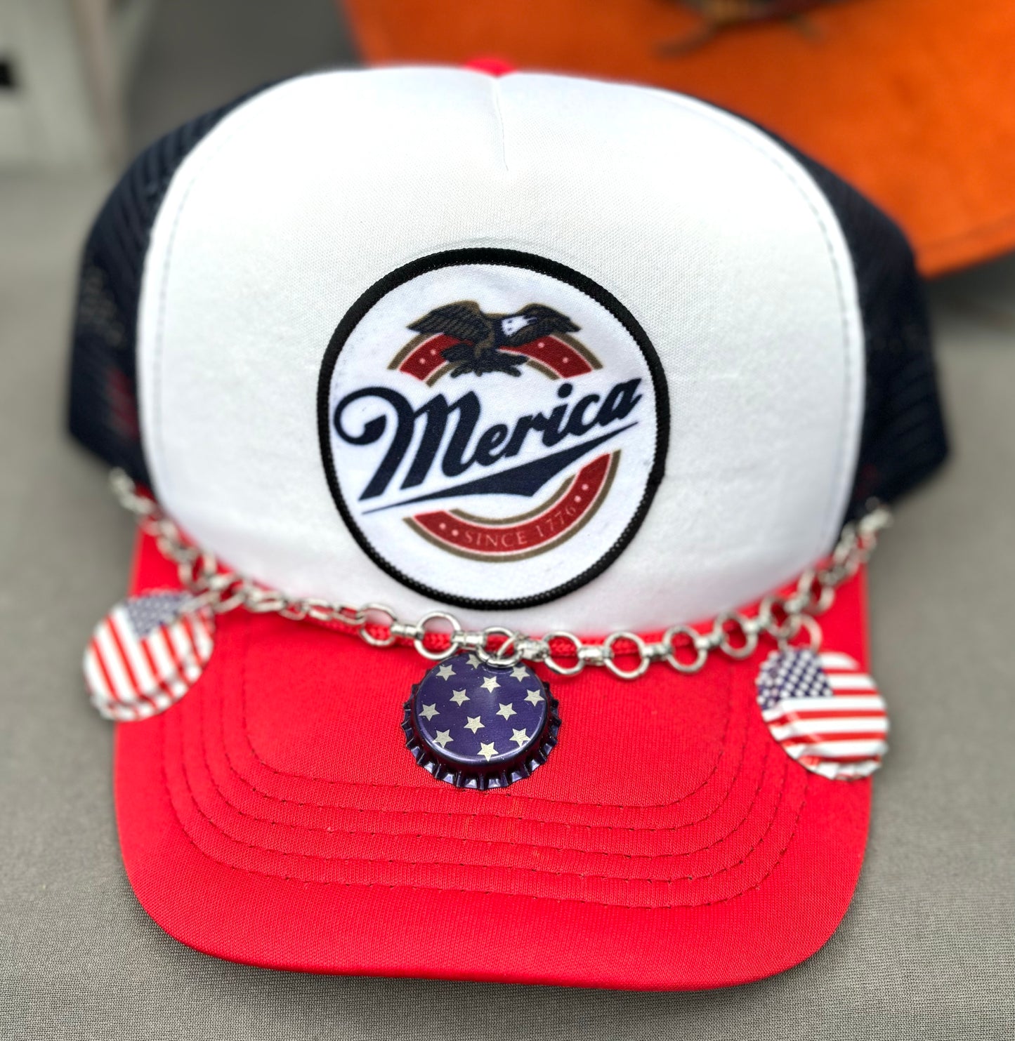 Custom trucker hat with a 'Merica' patch and American flag bottle cap chain band.