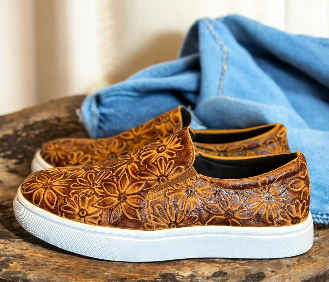 Brown sneakers on a wooden table with jeans.