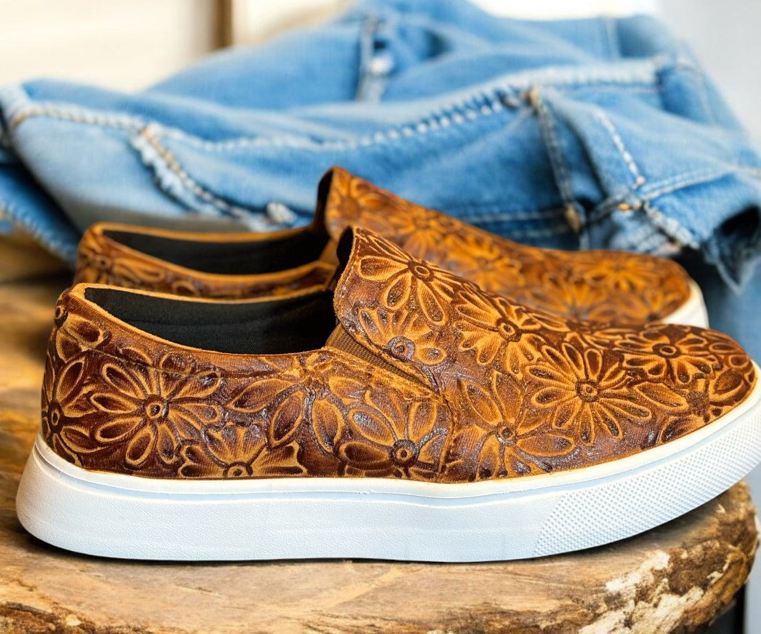 Brown sneakers on a wooden table with jeans.