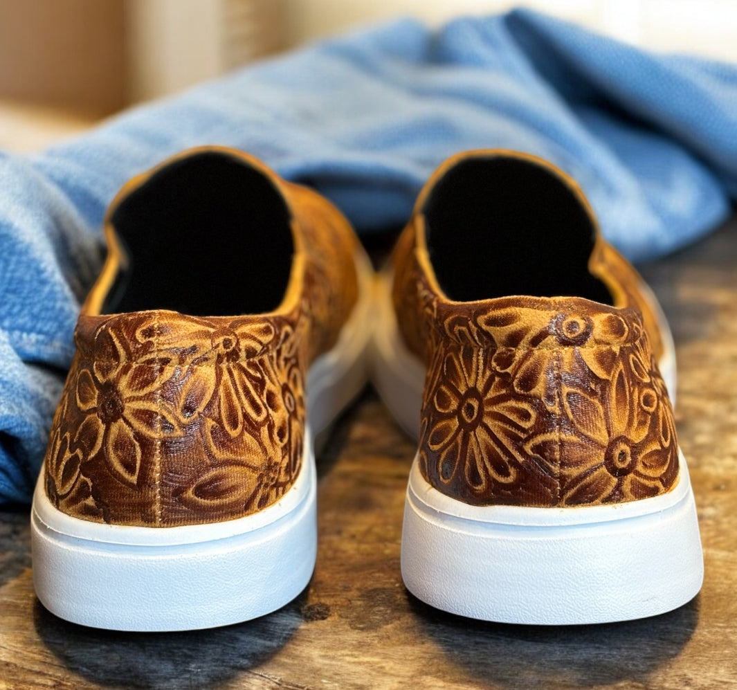 Brown sneakers on a wooden table with jeans.